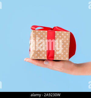 Small Christmas present in box wrapped in bow over blue Stock Photo