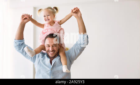 Millennial father riding his little daughter on shoulders Stock Photo