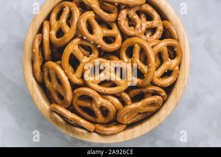 Traditional salty mini pretzels in wooden bowl on a gray backround. Stock Photo