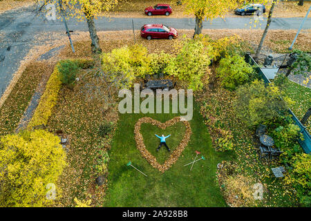 Person lying in heart made out of fallen leaves Stock Photo
