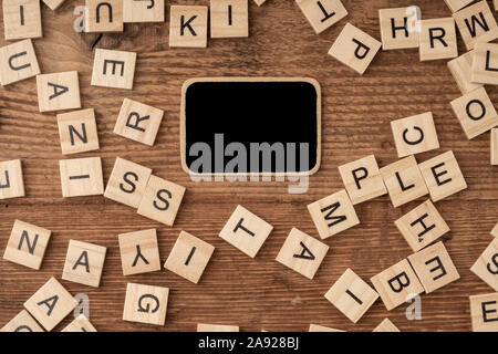 an empty chalkboard and cube alphabets on a wooden surface Stock Photo