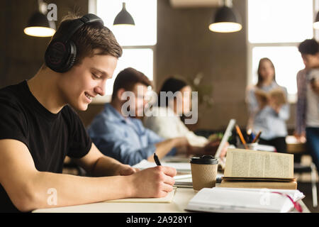 Student guy preparing for classes, taking notes in library Stock Photo