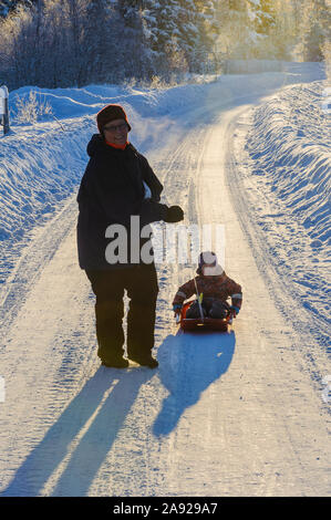 Mother pulling son on sledge Stock Photo