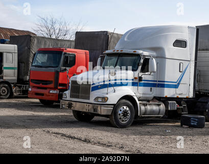 Modern trucks of various colors and models are involved for the transportation of different kinds of commercial goods are in a row on truck stop in Stock Photo