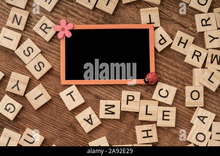 an empty chalkboard and cube alphabets on a wooden surface Stock Photo