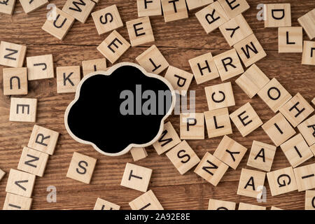 an empty chalkboard and cube alphabets on a wooden surface Stock Photo