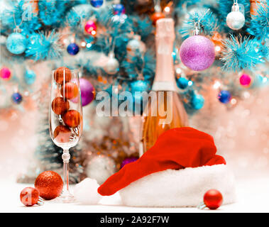 red glitter balls in a large wine glass against the background of a decorated blue Christmas tree Stock Photo