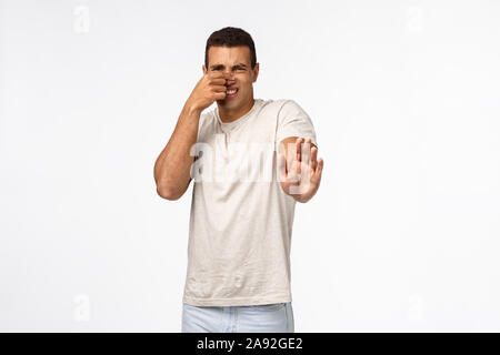 Guy feel disgusted from awful bad smell, rejecting stinky cheese plate,  close nose with fingers, shaking one hand in refusal, dislike gesture, step  Stock Photo - Alamy
