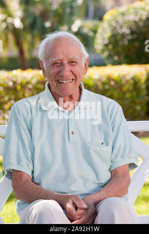 Portrait of an elder man sitting on a park bench and smiling Stock Photo