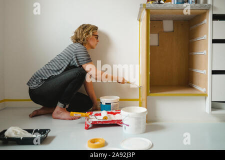 Woman painting cupboard Stock Photo