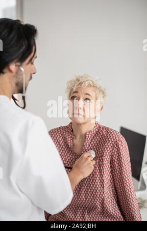 Doctor with stethoscope examining patient Stock Photo