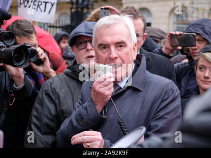 Westminster, London, UK. 12th November 2019. John McDonnell, Labour MP and Shadow Chancellor of the Exchequer addressing McDonalds employees from the London region striking in front of 10 Downing Streets promising reforms as part of a Labour government to increase minimum wages and protect the rates of the working poor. Placard with 'Poverty' in background Credit: JF Pelletier / Alamy Live News Stock Photo