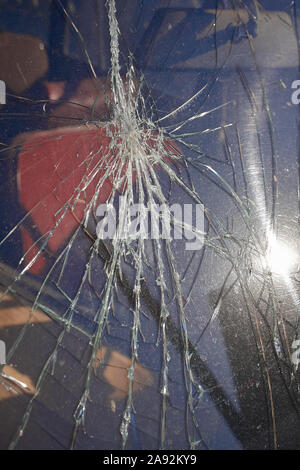 Cracks and glass shards radiate from the point of impact in a window that has been hit by an object Stock Photo