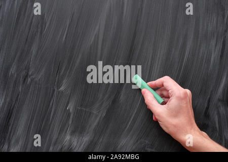 Hand writing on a black chalkboard with green chalk. Close up. Stock Photo