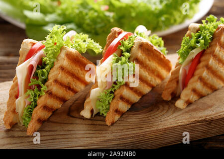 Fresh toast sandwich with cheese, ham and tomato on wooden background Stock Photo