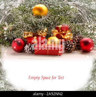 Christmas decorations of spruce twigs, snow, baubles and gifts with empty white space for text Stock Photo