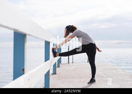 Woman stretching on jetty Stock Photo