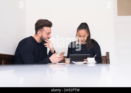 Couple in cafe using digital devices Stock Photo