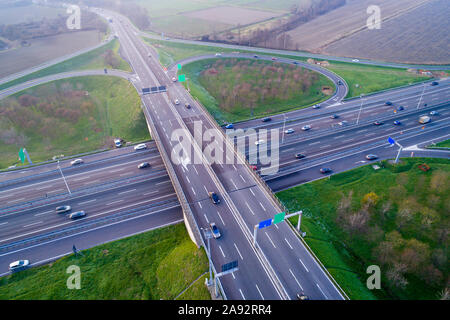 Cloverleaf interchange seen from above. Aerial view of highway road junction in the Po valley near Milan at sunset. Bird's eye view. Stock Photo