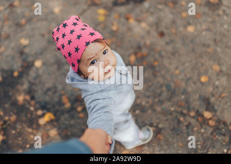 Cute 1 year old baby girl walking outdoors wearing in stylish overalls