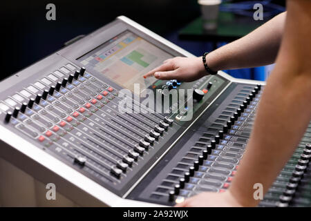 Operator working with compact digital broadcast audio console in studio. Selective focus. Stock Photo