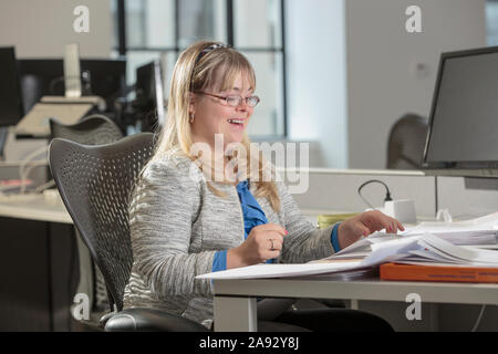 Young woman with Down Syndrome doing paperwork in an office Stock Photo