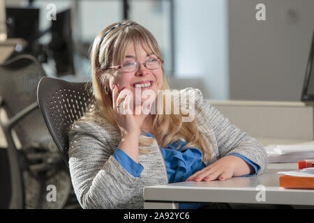 Happy young woman with Down Syndrome working in an office Stock Photo