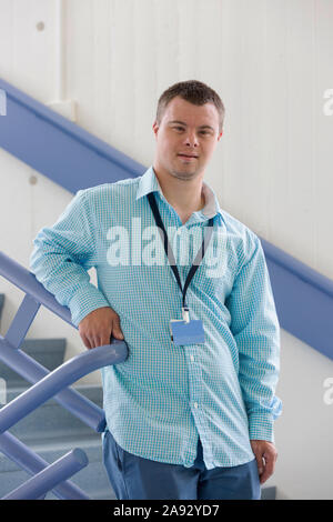 Young man with Down Syndrome working as a hospital aid on the stairwell Stock Photo