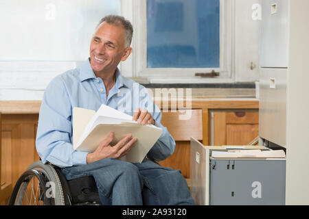 Project engineer with a Spinal Cord Injury in a wheelchair holding job files at the office Stock Photo