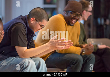 Black man with ADHD and Asian man with Autism and Caucasian with Cerebral Palsy and Non Verbal Learning Disorder laughing in a meeting Stock Photo