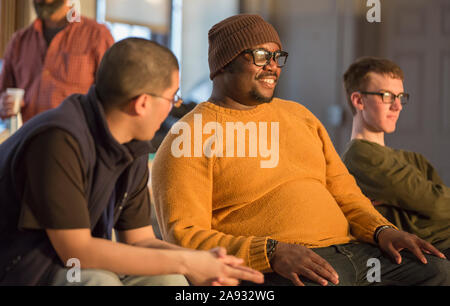 Black man with ADHD and Asian man with Autism and Caucasian with Cerebral Palsy and Non Verbal Learning Disorder talking in a meeting Stock Photo