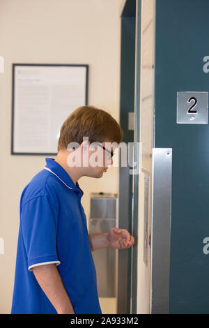 Young man with Down Syndrome using the elevator while working in a health clinic Stock Photo