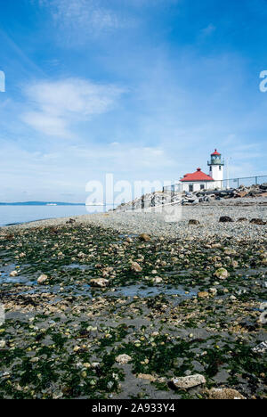 Alki Point Lighthouse in West Seattle, Washington.  There are two ferry boats in the Puget Sound in the background. Stock Photo