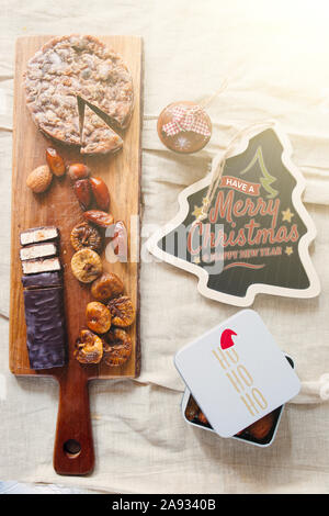 christmas dried dessert on a cutboard, typical italian sweeties offered at the end of christmas dinner,Nougat ,dried fruit ,panforte and dates, top vi Stock Photo