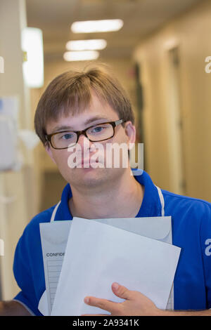 Young man with Down Syndrome delivering paperwork in a health clinic Stock Photo