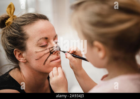 Girl painting mothers face Stock Photo