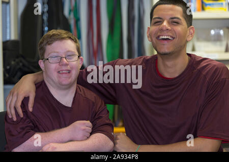 Young man with Down Syndrome having fun with supervisor at college equipment dispensary Young man with Down Syndrome having fun with supervisor at college equipment dispensary