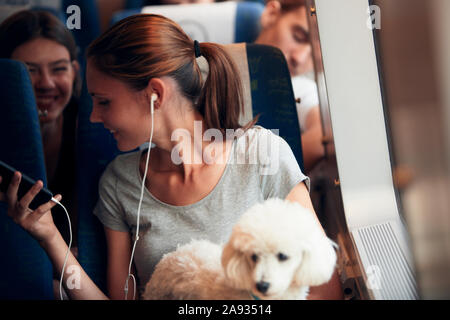 Smiling woman using phone in train Stock Photo