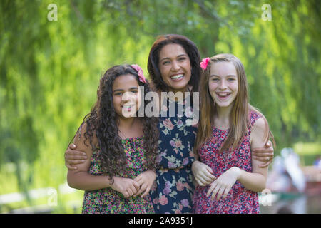 Portrait of happy Hispanic mother and two teen daughters with braces in park Stock Photo