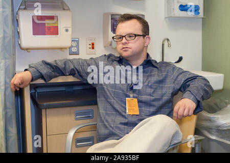 Hospital aid worker with Down Syndrome relaxing at work in office Stock Photo