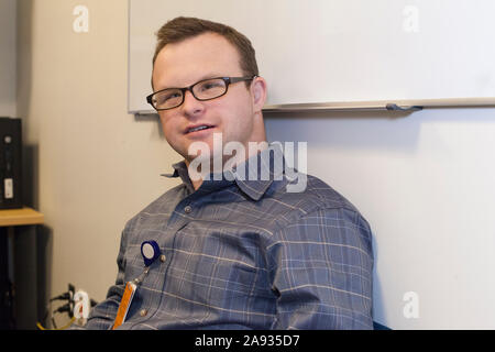 Hospital aid worker with Down Syndrome relaxing at work in office Stock Photo