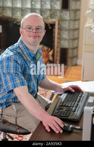 Man with Down Syndrome working at his computer in an office Stock Photo