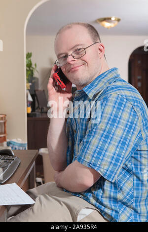 Man with Down Syndrome talking on his cell phone in an office Stock Photo
