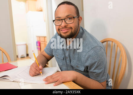 Happy African American man with Down Syndrome doing paperwork at home Stock Photo