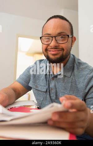 Happy African American man with Down Syndrome doing paperwork at home Stock Photo