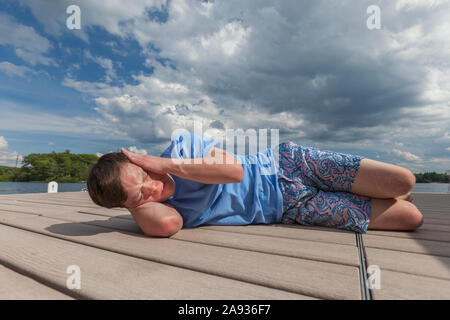 Young man with Down Syndrome playing on a dock Stock Photo