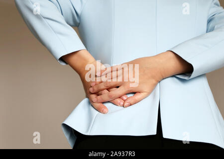 Back pain, woman in office suit suffering from backache. Female hands holding lower back, kidney or spine disease Stock Photo