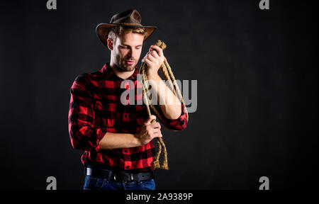 handsome rancher. western cowboy portrait. wild west rodeo. man in hat black background. cowboy with lasso rope. Western. man checkered shirt on ranch Stock Photo