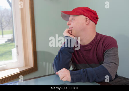 Happy young man with Down Syndrome sitting at home Stock Photo