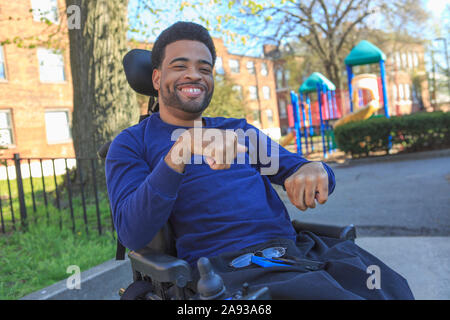 Happy African American man with Cerebral Palsy using his power wheelchair outside Stock Photo